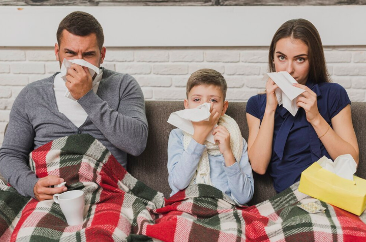 Image of a family sitting on the couch with the flu. 