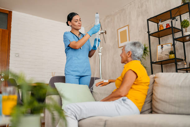 A nurse prepares a mobile IV treatment for an elderly woman at home.