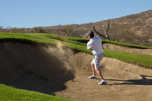 A man takes a shot from the sand bunker.