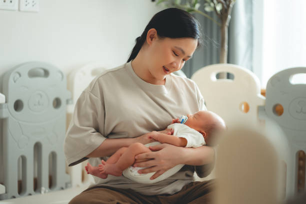 A new mom rocks her newborn baby to sleep in her home. 