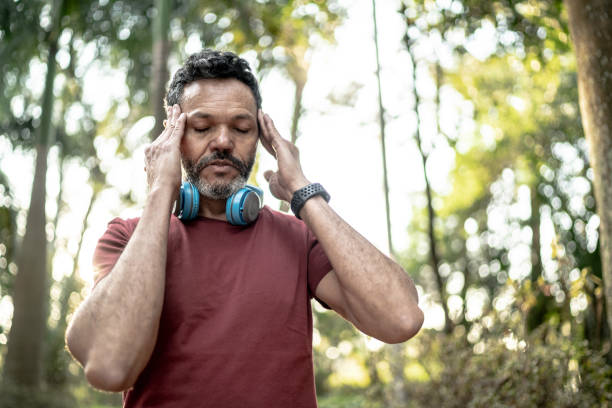 A man with headphones struggles with an altitude headache while working out. 